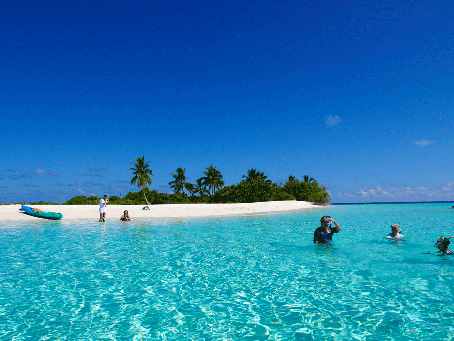 Resenärer som snorklar i kristallklart vatten på Zanzibar nära Mnemba Atoll