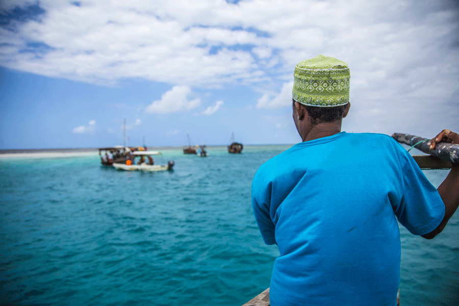 Närbild på en rustik trädhow förtöjd i sanden vid lågvatten på Jambiani-kusten