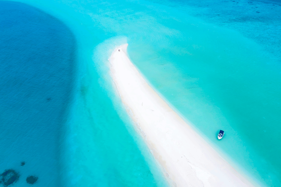Vit sand och grunt turkost vatten vid Nakupenda på Zanzibar
